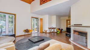Amplia sala de estar con chimenea, televisor y un ventanal.