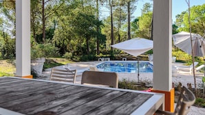 Un espacio al aire libre cubierto con piscina, sillas de descanso y sombrillas.