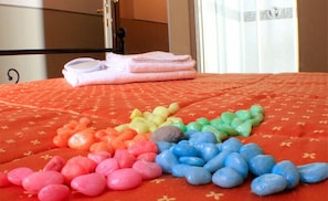 A bed with a red bedspread and a row of colorful stones arranged in a pattern. - Hotel Da Benito (Norcia)