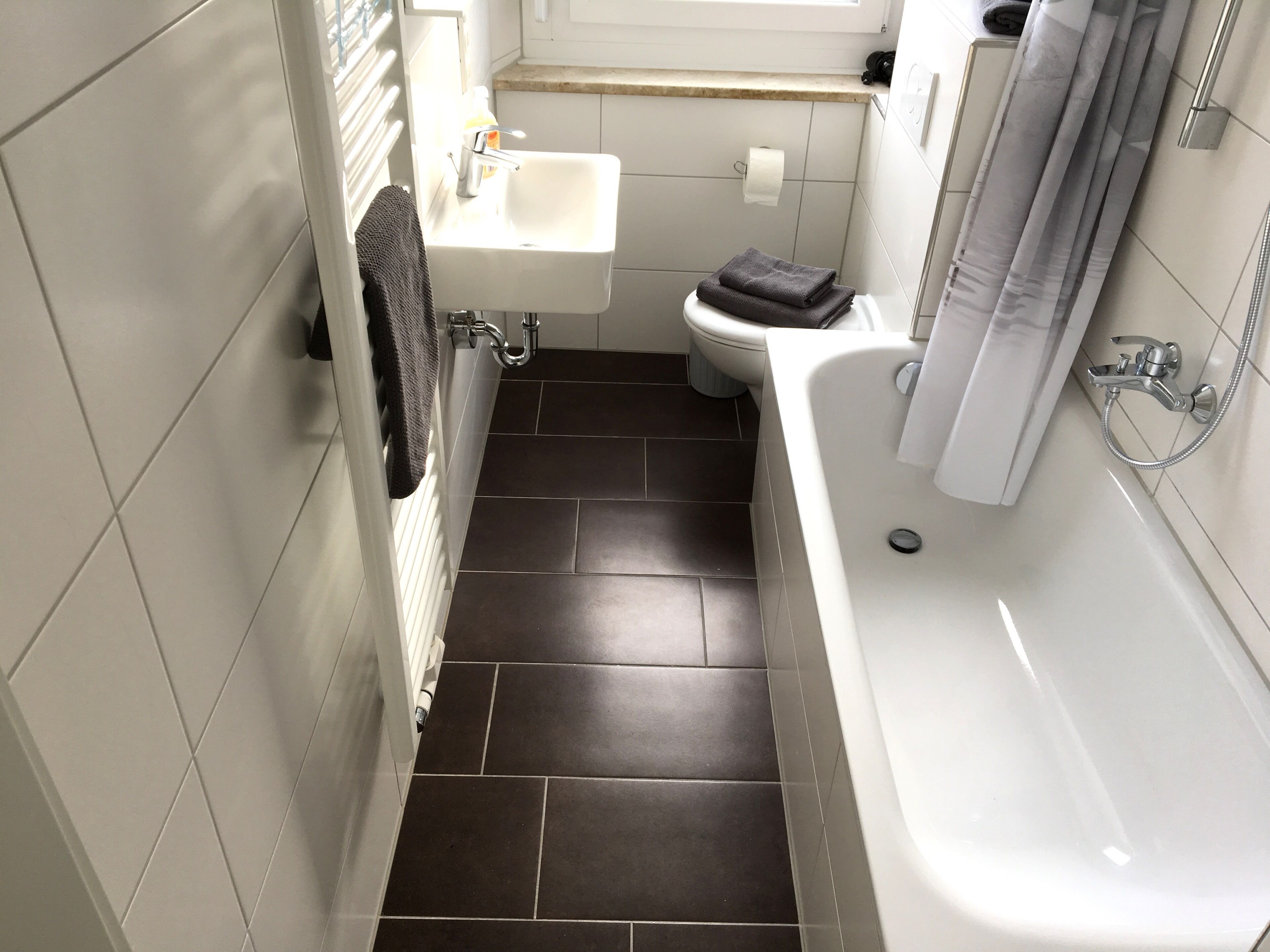 Une salle de bain avec un lavabo blanc, des toilettes et une baignoire.