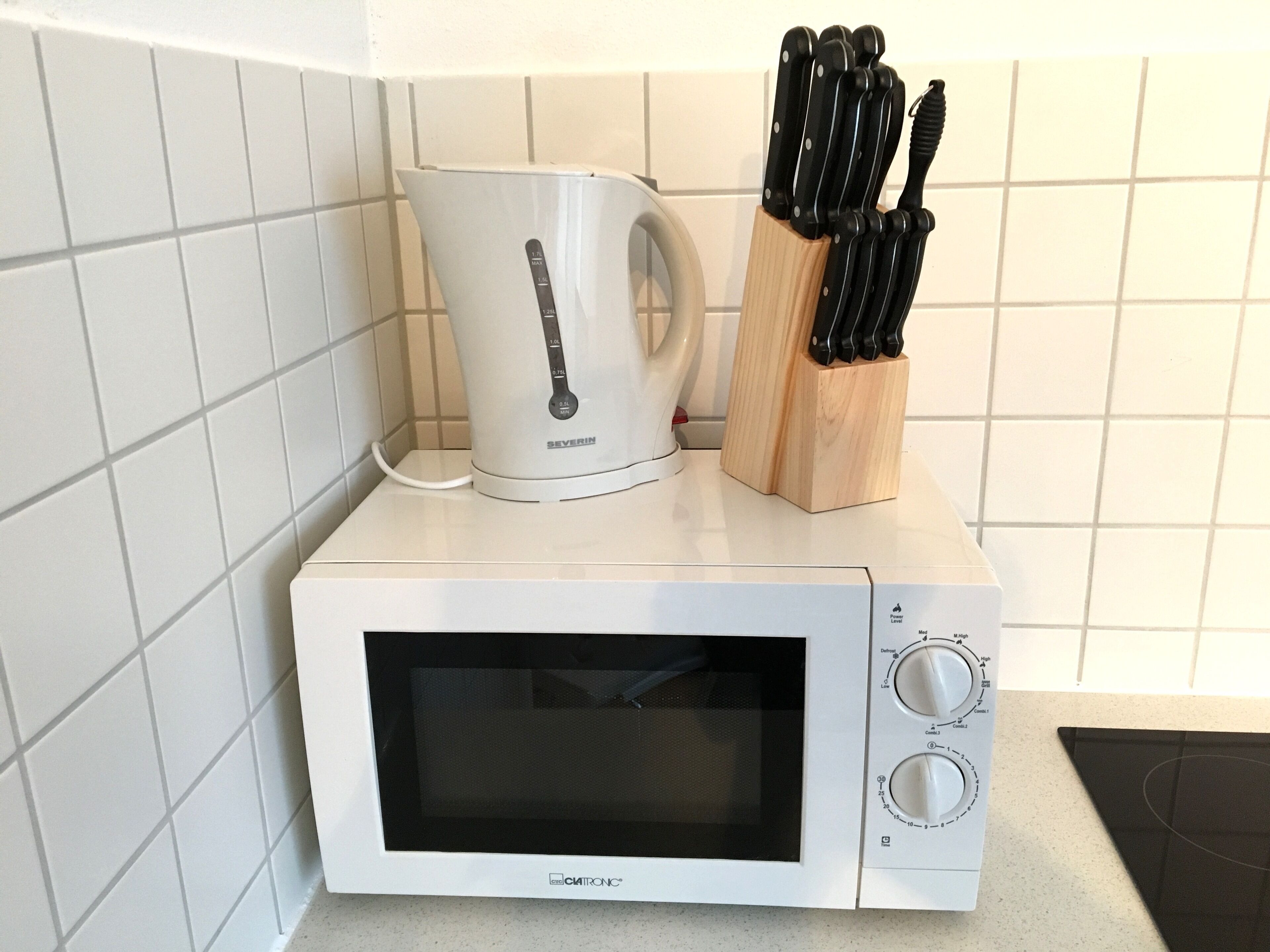 A compact microwave oven with a digital display and control knobs, placed on a kitchen counter.