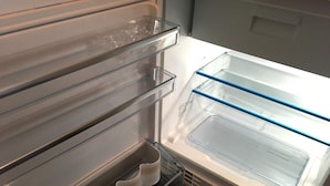 Jääkaappi, jossa on läpinäkyvät hyllyt ja erillinen pakastinosa.