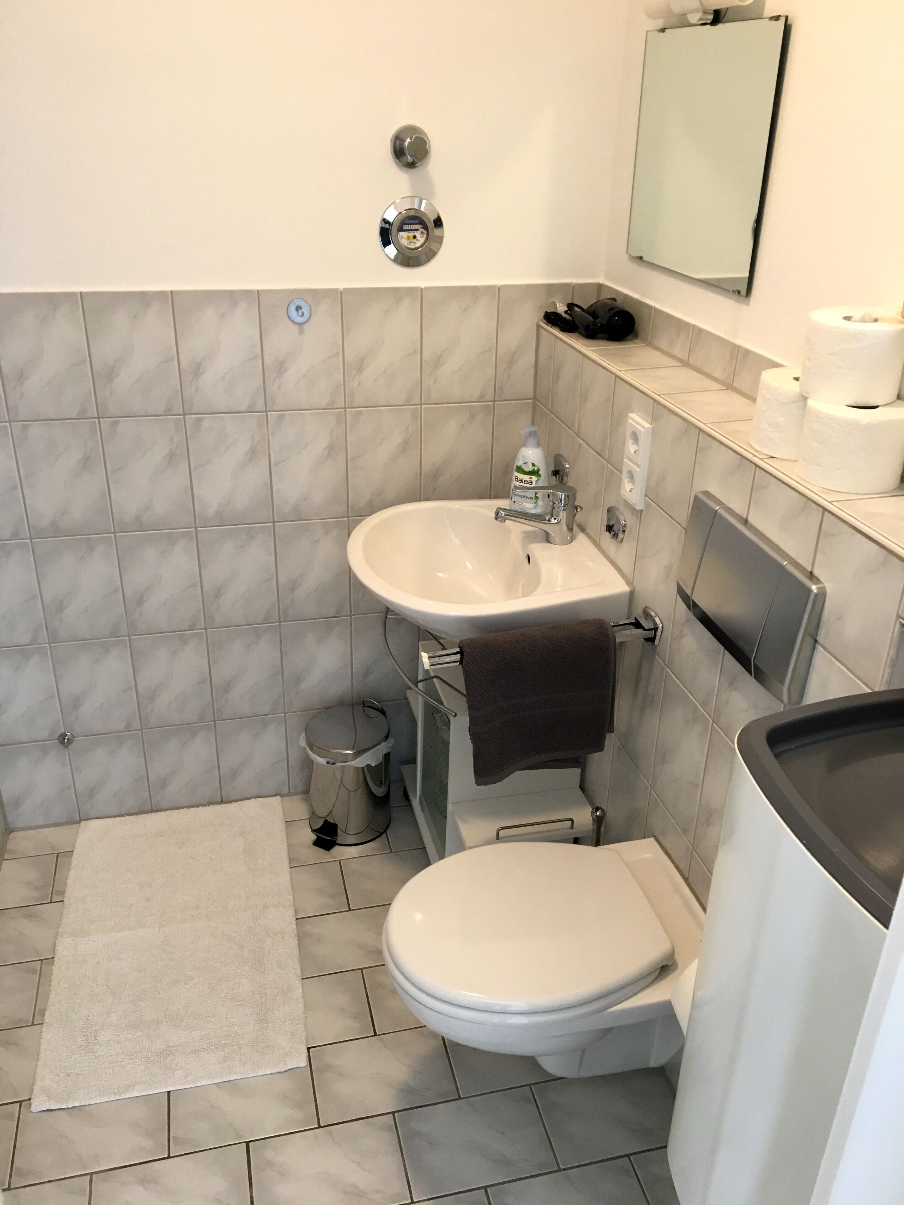 Une petite salle de bain avec des toilettes, un lavabo et un miroir.