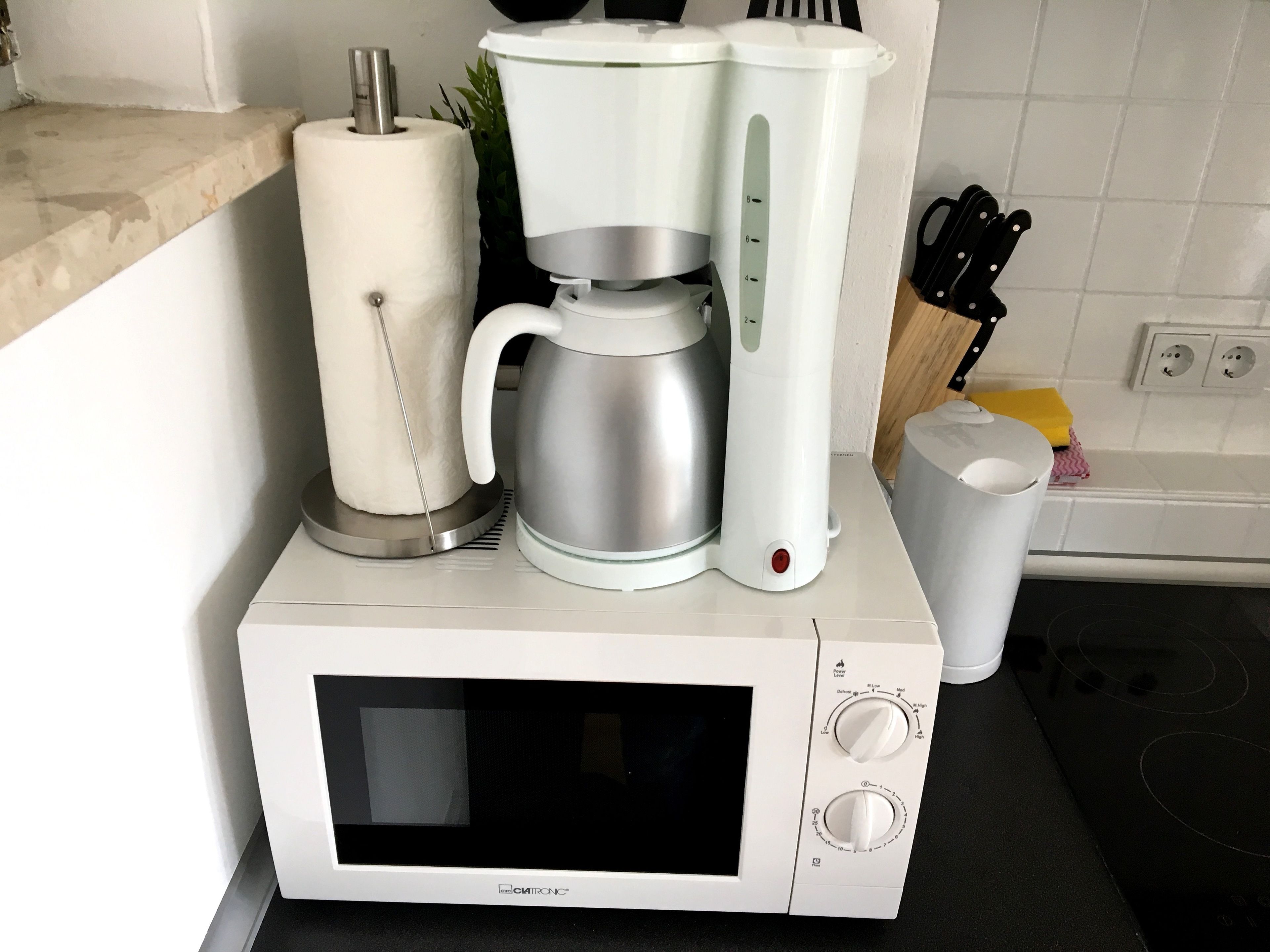 A kitchen with a microwave, coffee maker, and a trash bin.