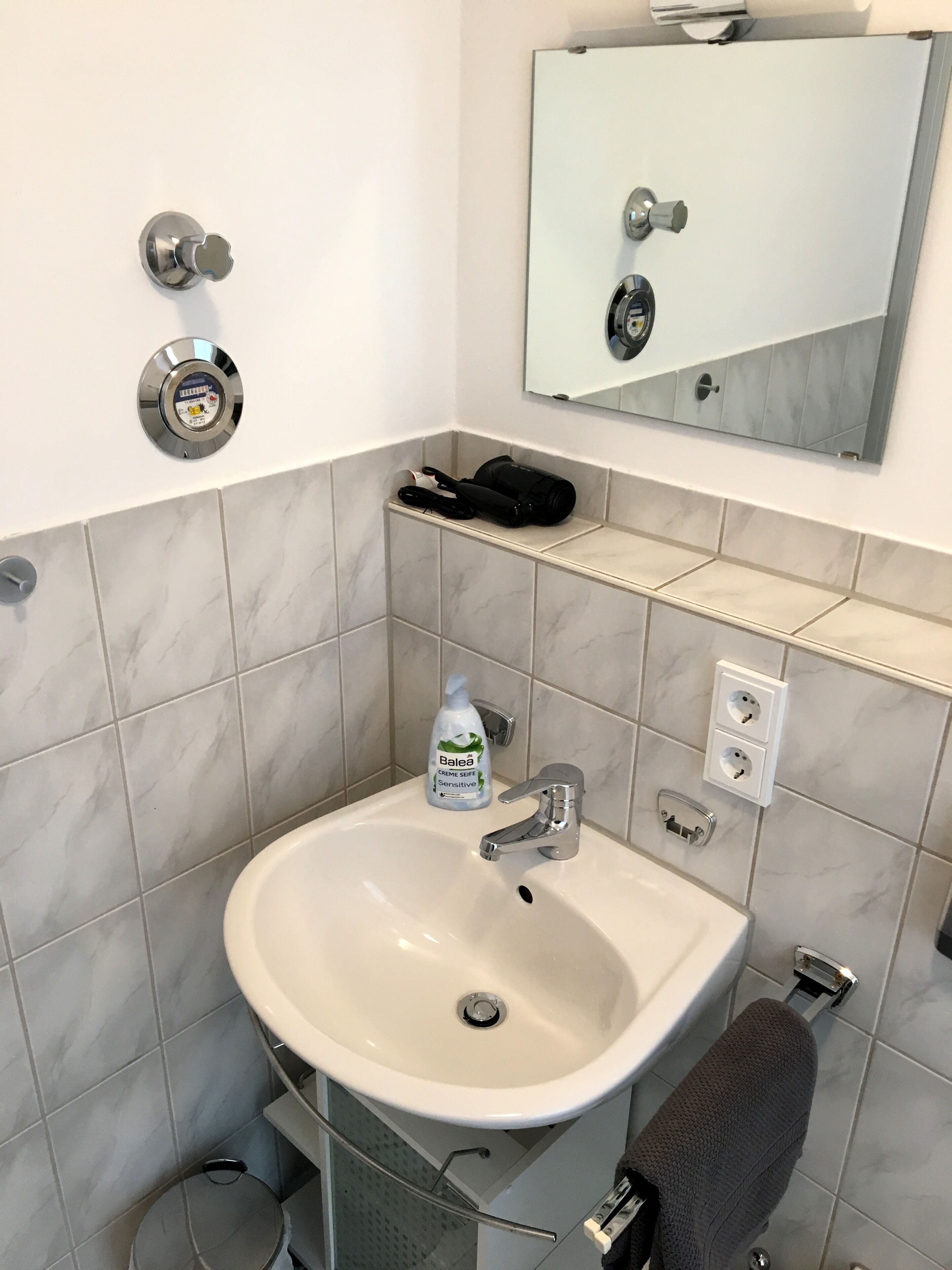 A bathroom with a white sink, a mirror, and a towel rack.