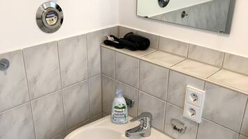 A bathroom with a white sink, a mirror, and a towel rack.