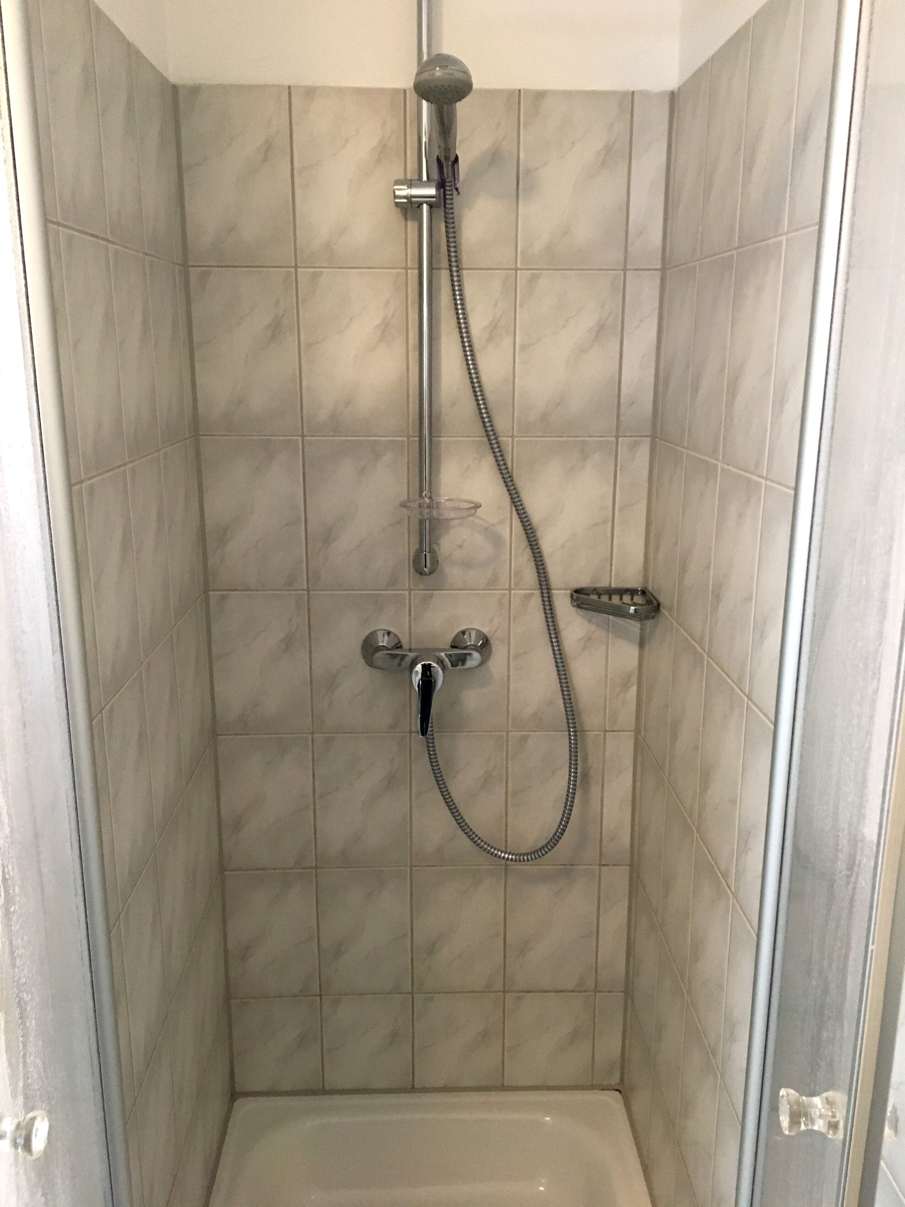 Eine Dusche mit Duschkopf, Wandarmatur und Duschschlauch.