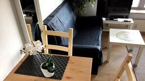 A dining area with a wooden table, black placemats, and a potted plant. - Downtown (Regensburg)