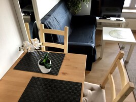 Un comedor con una mesa de madera, individuales negros y una planta en maceta.