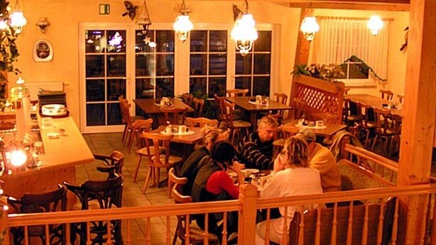 A restaurant with multiple tables and chairs, a wooden railing, and large windows. - Hotel Märkischheide GmbH (Vetschau/Spreewald)