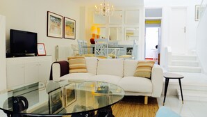 A modern living room with a glass coffee table, a white sofa, and a television on a cabinet. - VILLA LOS REMOS SEAVIEW (Mojácar)
