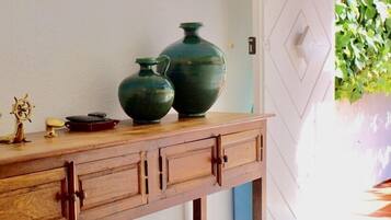 Een houten console tafel met twee groene vazen en een klein scheepsmodel.