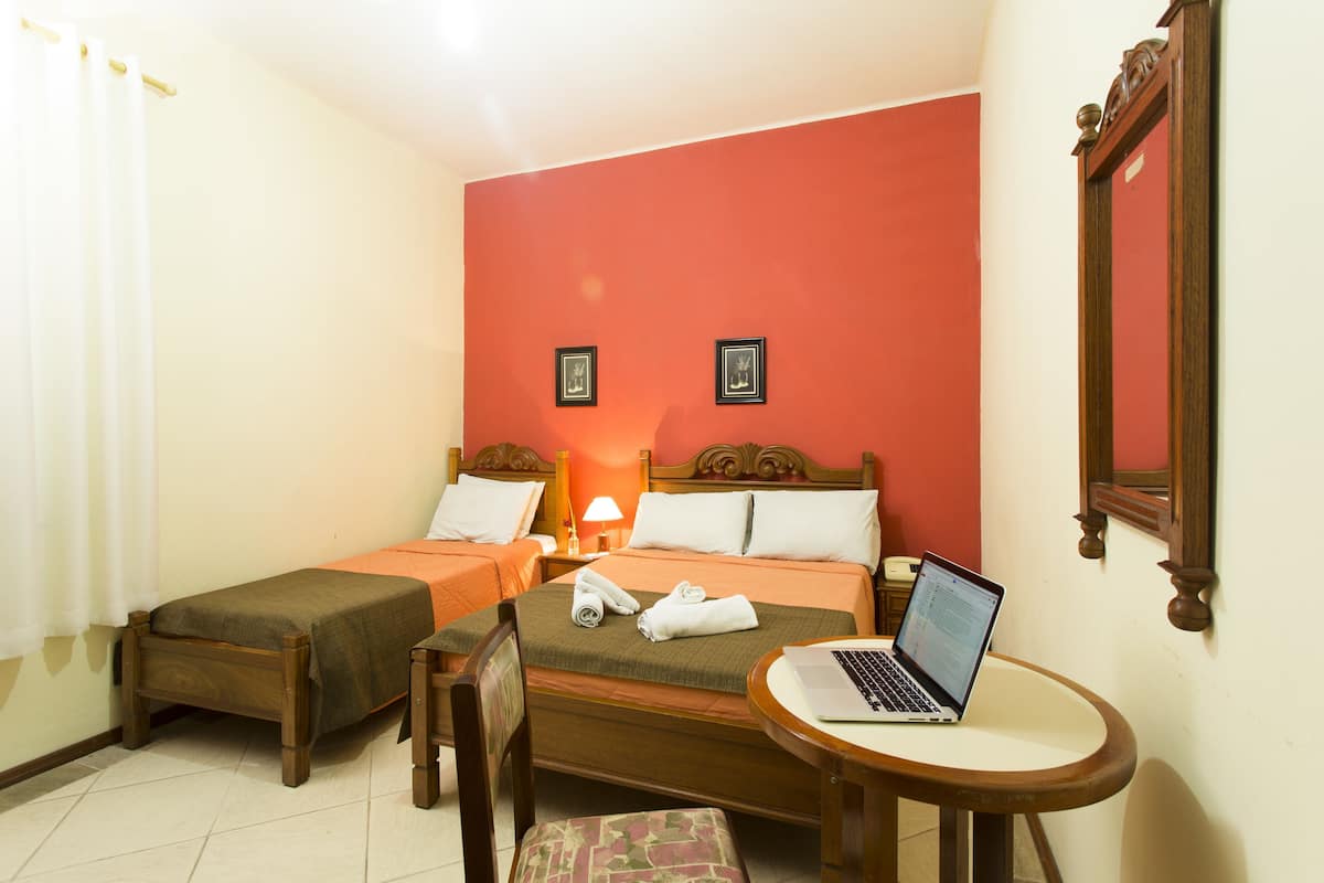 Ein Hotelzimmer mit zwei Betten, einem Schreibtisch, einem Stuhl und einem Laptop.