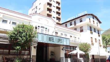 Ein Hotel mit markantem Eingang, einer Außenbereich-Sitzgelegenheit und einem mehrstöckigen Gebäude im Hintergrund.