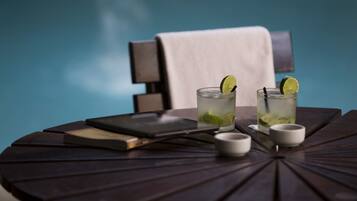 Une table ronde avec deux verres d’une boisson à base de citron vert, un livre et un petit bol.