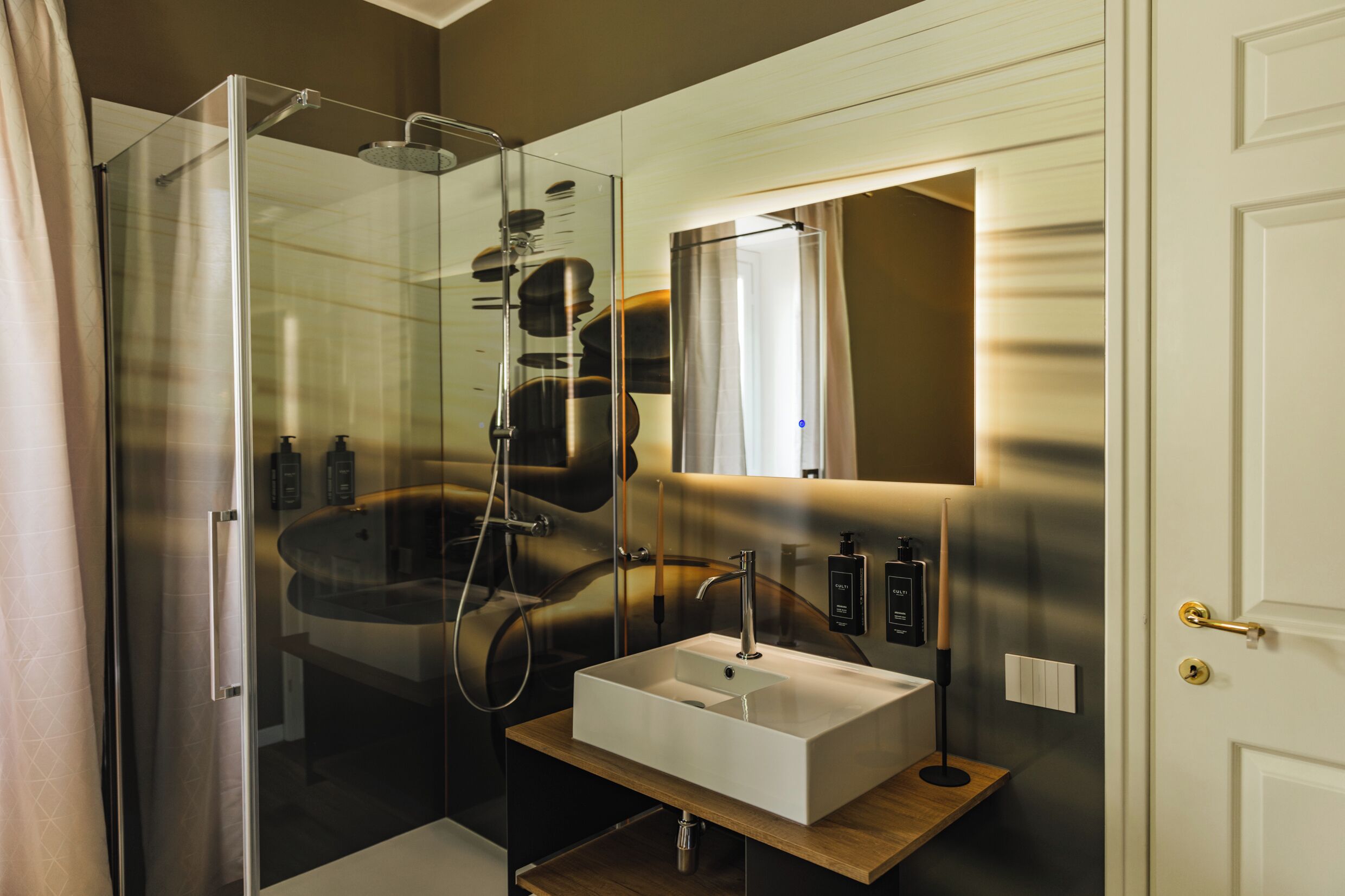 A modern bathroom with a glass-enclosed shower, a white sink, and a mirror above it.
