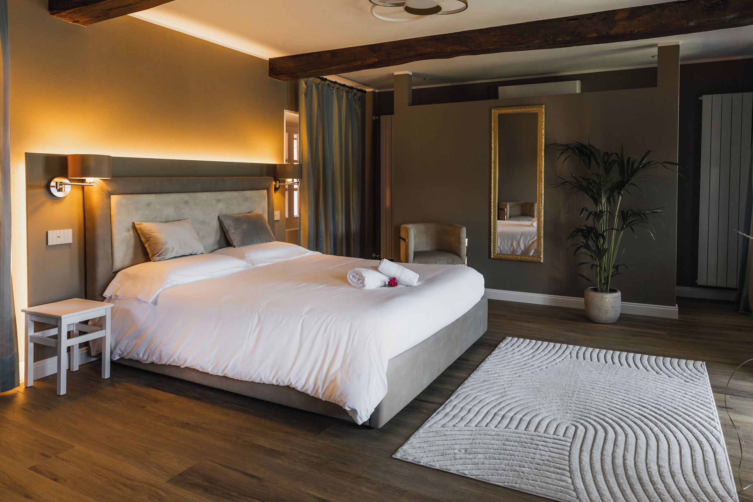 Ein modernes Hotelzimmer mit einem großen Bett, einem Nachttisch, einem Spiegel und einer Topfpflanze.