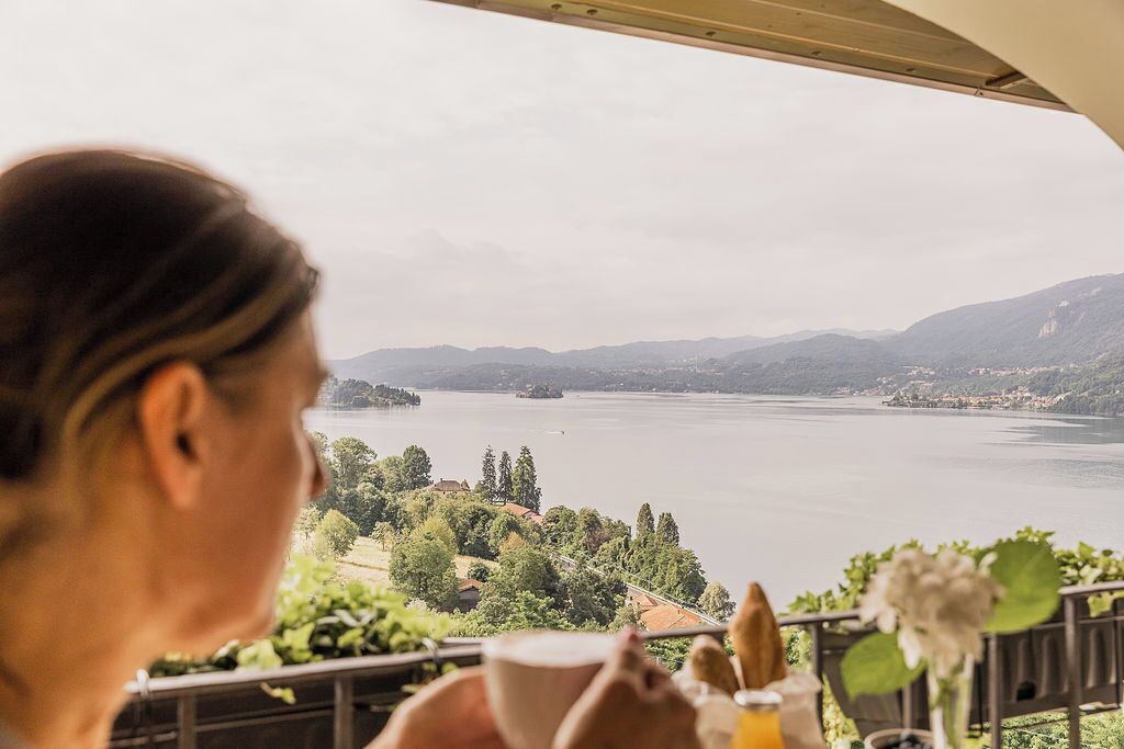 A person dining at a table with a view of a lake and surrounding landscape.
