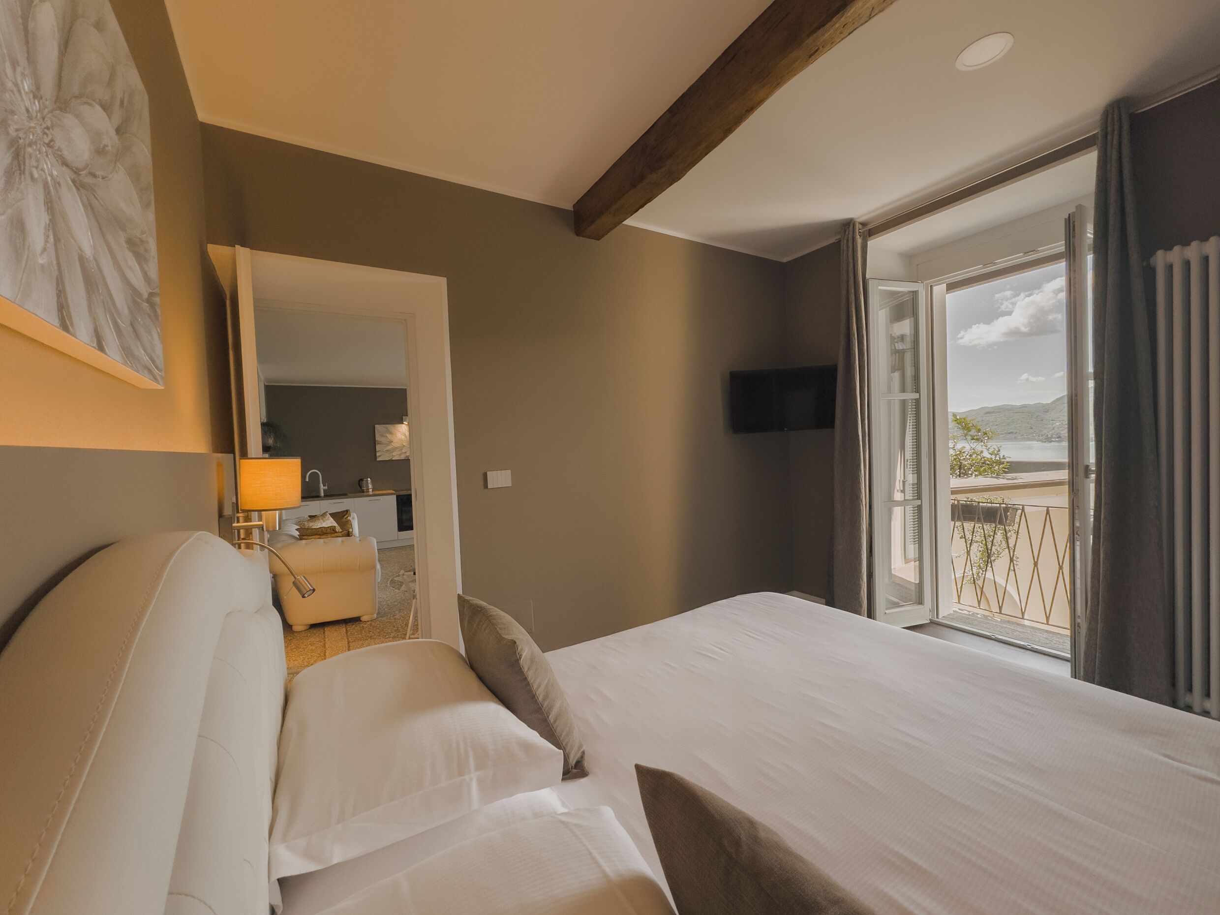 A hotel room with a bed, a desk, a mirror, and a TV.