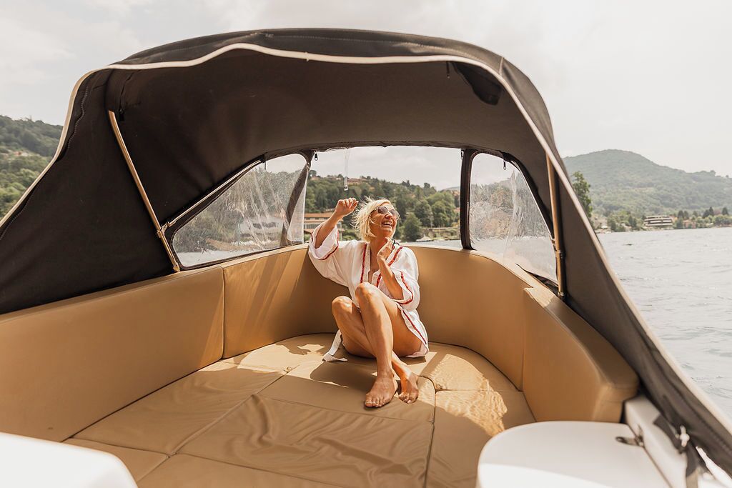A person sitting on a boat with a canopy, surrounded by water and greenery.