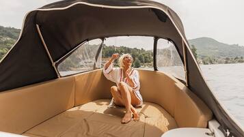 A person sitting on a boat with a canopy, surrounded by water and greenery.