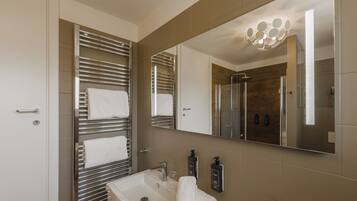 A modern bathroom with a large mirror, a sink, and a shower.