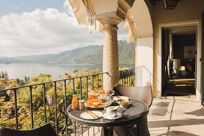 A balcony with a table set for breakfast, overlooking a lake and mountains. - Villa Antica Colonia (Pettenasco)