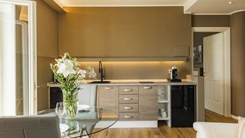 Una cocina moderna con lavavajillas incorporado, cafetera y un florero con flores en la encimera.