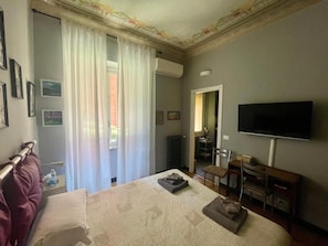 A hotel room with a bed, a television, a desk, and a chair. - B&B U Sentè (Genoa)