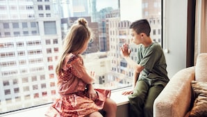 Dos personas sentadas junto a una ventana con vista a un paisaje urbano.