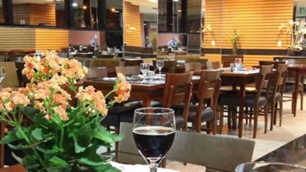 Une table à manger avec une plante en pot, des verres à vin et des couverts.