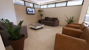 Un salon moderne avec un canapé, des fauteuils, une table basse et des plantes en pot.