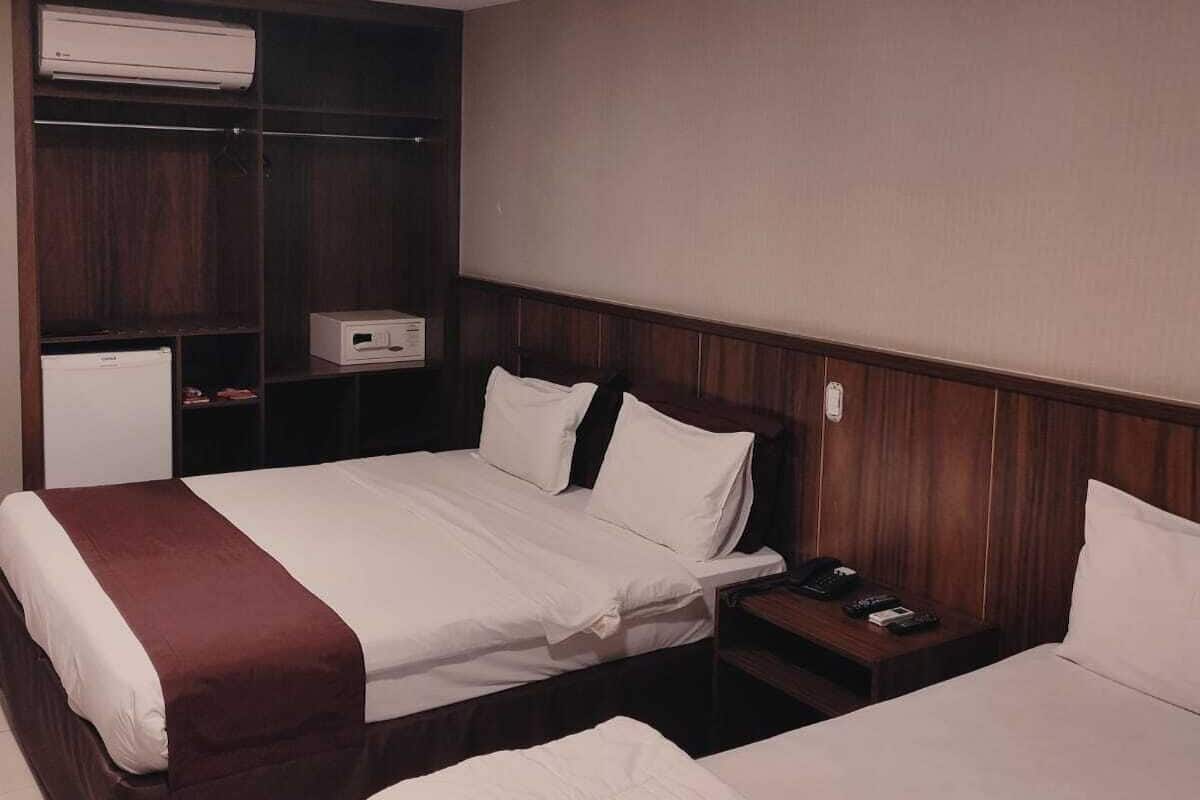 Une chambre d’hôtel avec deux lits, une armoire, un bureau avec un téléphone et un appareil de climatisation.