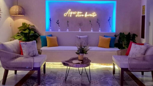 A modern living room with a neon sign, two armchairs, a sofa, and a coffee table. - Hotel Yaxactun (Progreso)