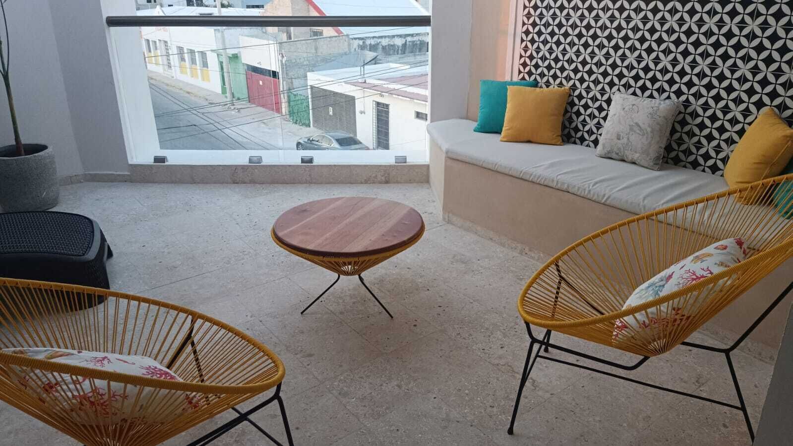 A balcony with wicker chairs, a small round table, and a sofa with cushions.