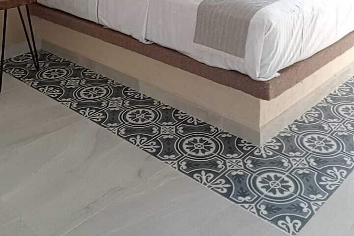 Un dormitorio moderno con una cama grande, cabecera de madera, alfombra estampada y lámpara colgante.