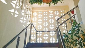 A staircase with a railing, surrounded by a lattice wall and hanging green foliage. - Hotel Yaxactun (Progreso)