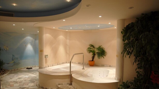 Een wellnessruimte met twee whirlpools, een stenen vloer en een muurschildering van vissen.