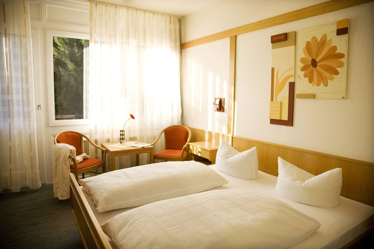 Camera d'albergo con due letti, una scrivania e due sedie.