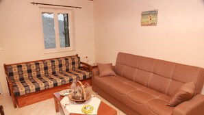 A living room with a sofa, a wooden table, and a window. - Mary's Villas (Lesvos)