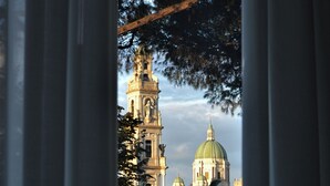 Blick auf eine Kirche mit Glockenturm und Kuppel durch ein Fenster mit Vorhängen.