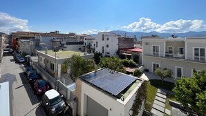Ein Wohngebiet mit einer Straße, gesäumt von parkenden Autos, Gebäuden mit Solaranlagen und freiem Blick auf die Berge im Hintergrund.