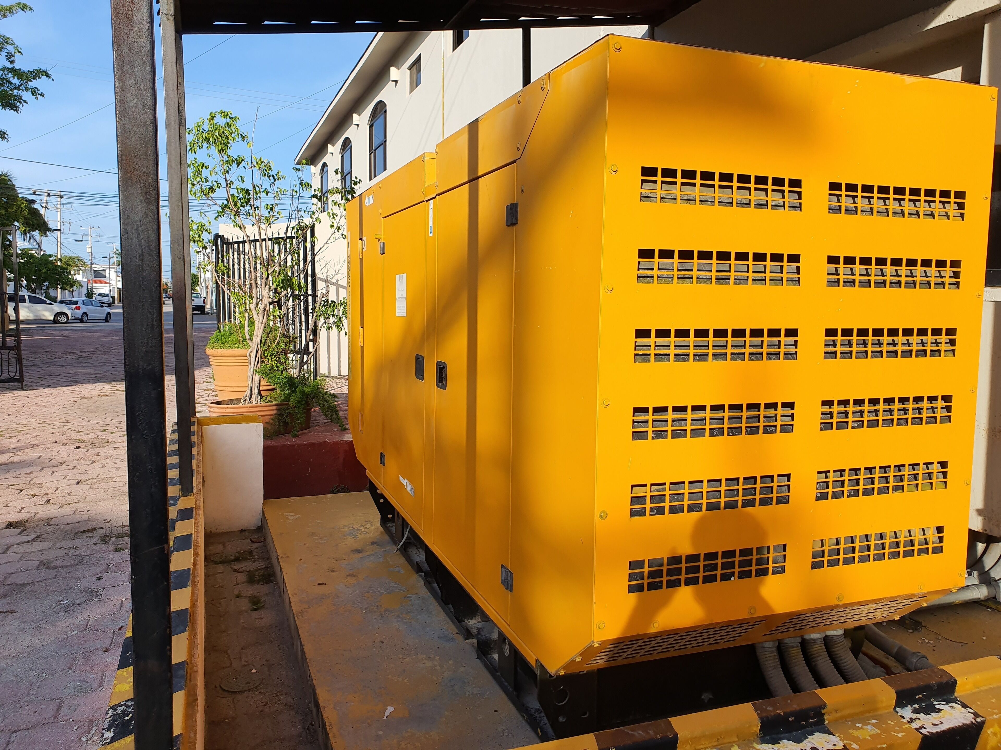 A large yellow electrical box with ventilation grilles, mounted on a platform with a metal railing.