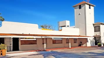 Un hotel con fachada blanca, una torre de campanas y un cartel que indica que es un hotel.