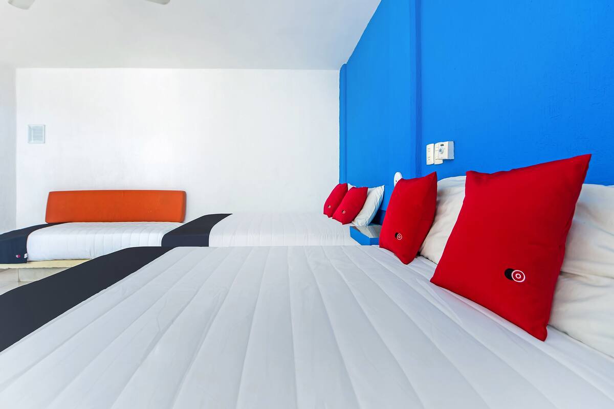 Una habitación de hotel con una cama grande, un ventilador de techo y una pared azul decorativa.