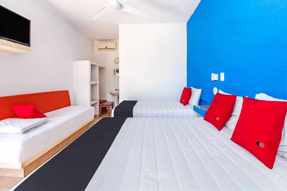 Una habitación de hotel moderna con una cama blanca, un sofá rojo y una pared decorada en azul.
