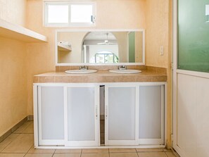 Un baño con dos lavabos, un espejo grande y armarios.