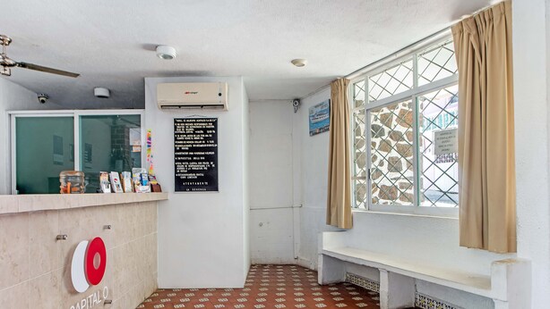 Een hotel receptie met betegelde vloer, een receptiebalie, een raam met gordijnen en een airconditioning.