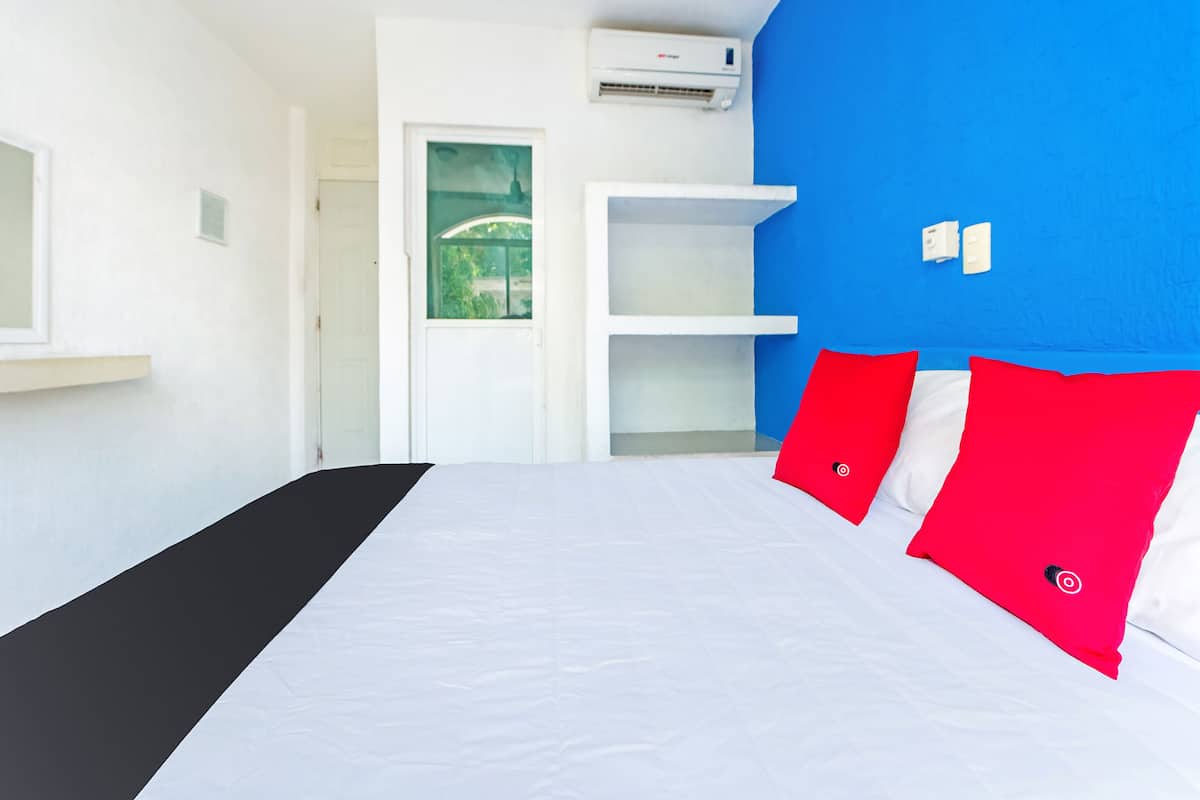 Una habitación de hotel moderna con una cama, un ventanal, una puerta y un equipo de aire acondicionado.