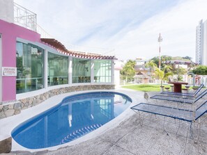 A swimming pool with a stone wall and a glass enclosure. - Capital O Hotel El Mejicano, Acapulco (Acapulco)